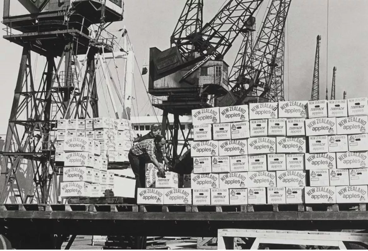 Historic image of the Port of London with apples stacked up in front of cranes