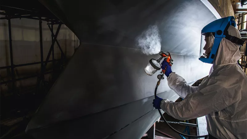 A Goodchild Marine employee applies a protective coat to a vessel hull.