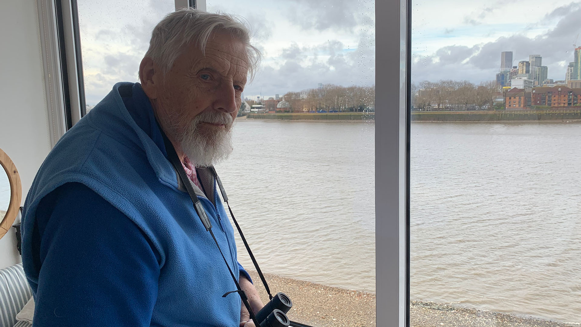 Peter Kent with binoculars and river Thames in the background