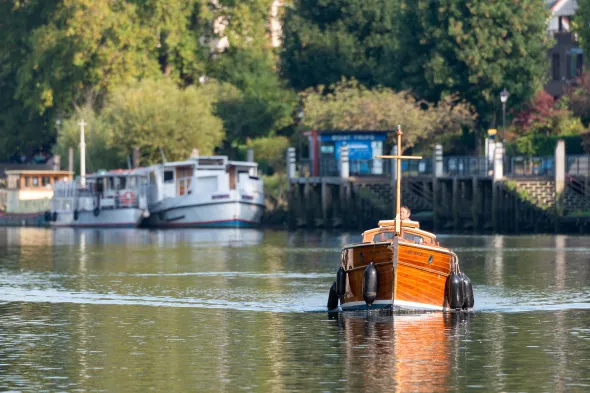 Classic wooden boat cruising on the tidal Thames