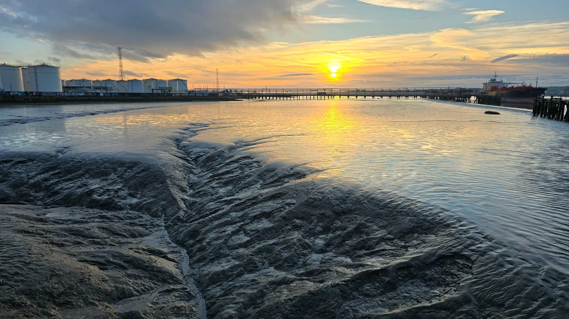 Sunrise, mud flats, fuel tanks