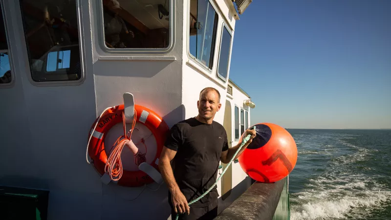 Andrew Lawrence on board a vessel holding a buoy