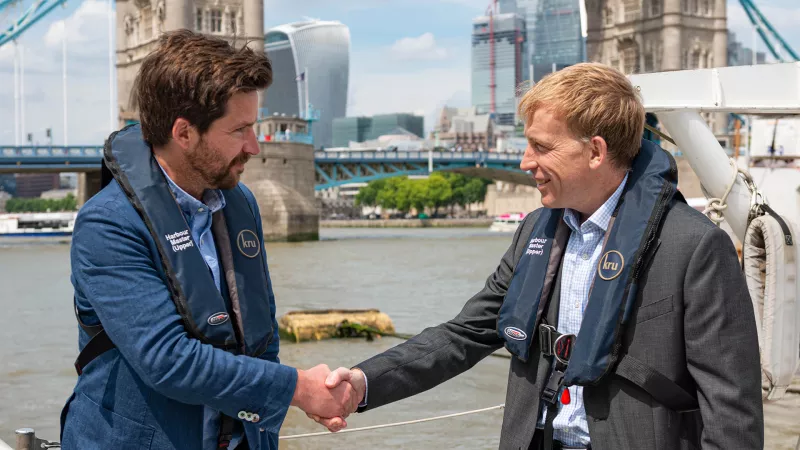 Miles Cole and Robin Mortimer shake hands while on the river in central London